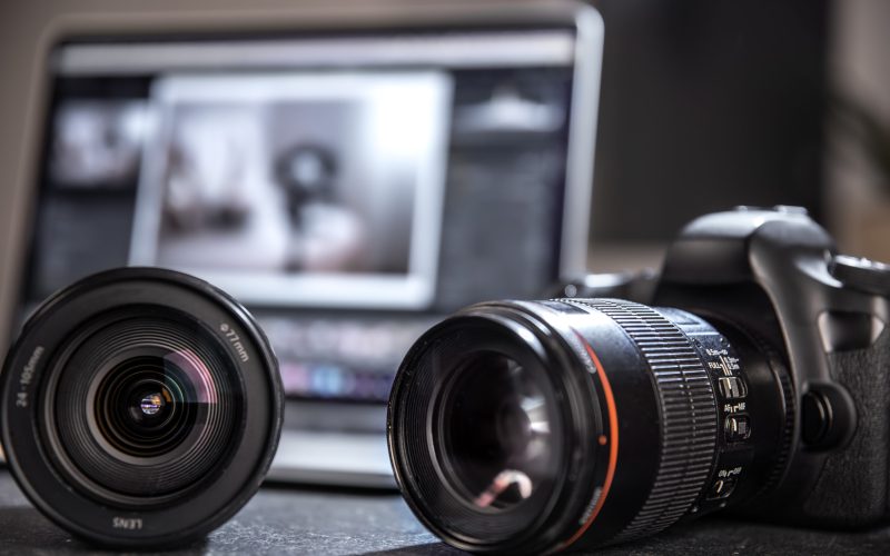 Professional camera and lens close-up on a photographer's desktop on a blurred background. The concept of professional equipment for photo and video.