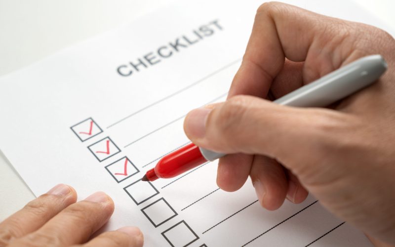 Hand with red marker pen marking on checklist sheet